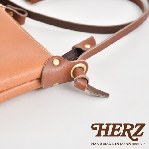 職人手作皮革直式隨身單肩包，經典棕色皮革，搭配同色系縫線及銀色金屬拉鍊，展現細膩工藝。