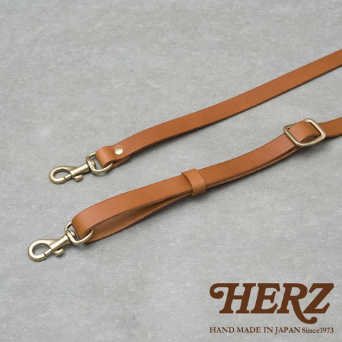 兩條棕色皮革提把，配有金色鉤扣和可調節扣環，展示於灰色背景上。