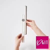 一雙手正操作著白色塑膠材質的刮水器，刮水器上有一個灰色圓形磁吸旋鈕，刮水條為深灰色。