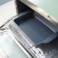 深灰色陶製長方形烤盤，內部平坦，邊緣略有弧度，置於烤箱內的金屬網架上。