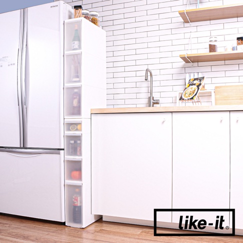 白色疊疊三抽夾縫收納櫃，置於冰箱與廚櫃之間，櫃體為透明塑膠材質，內有瓶裝醬料、檸檬、罐裝食品等物品。