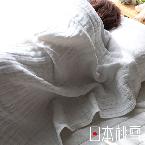 一位女子蓋著日本桃雪五層紗透氣單人被，被子為白色，有明顯的織紋，背景光線明亮。