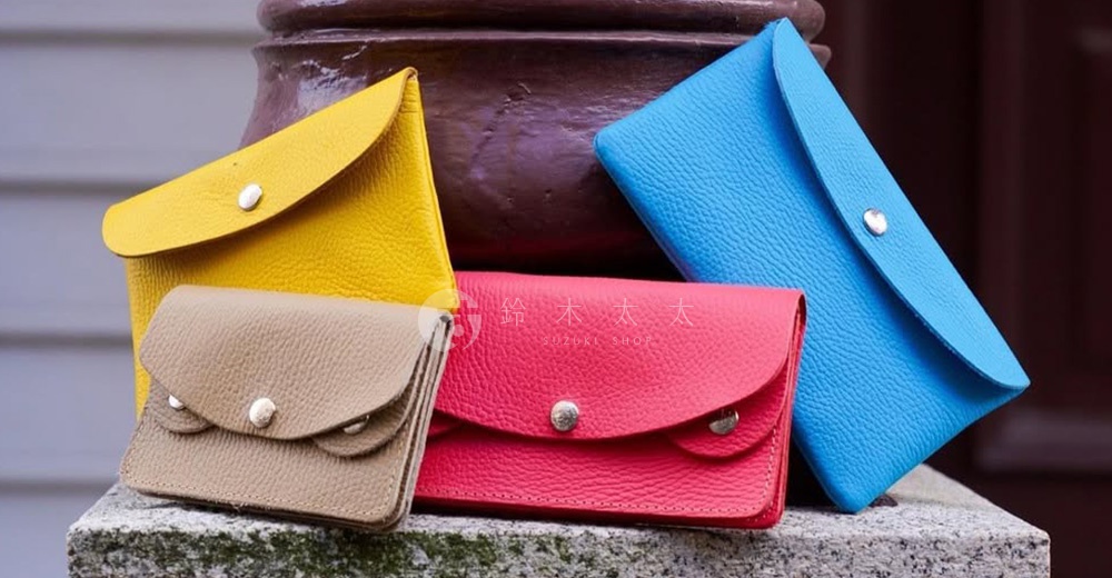 四款皮革零錢包，分別為黃色、卡其色、桃紅色和藍色，皆採用荔枝紋皮革材質，並以金屬釦固定。