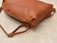 棕色皮革後背包，帶有拉鍊開口和可調節的皮質肩帶，肩帶上有金屬扣環。