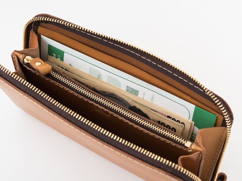 職人手作皮革大容量拉鍊長夾 (WL-5)，採用淺棕色皮革製成，設有多個隔層，並可見部分日圓鈔票與綠色文件。
