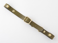 橄欖綠皮革製成的背包減壓胸前扣帶，配有黃銅色金屬扣環、鉚釘和 D 型環。