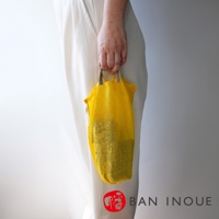 黃色網狀提把蔬果收納袋，底部有黑色網格印花，兩側有織帶提把，適合攜帶和保存蔬果。