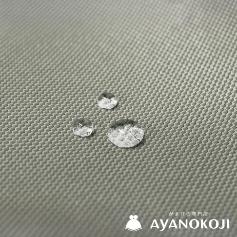 有三顆水珠落在米灰色機能布料上，布料表面有細密的編織紋理，右下角有日文及 AYANOKOJI 品牌標誌。