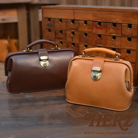 兩款職人手作皮革方型迷你醫生包，一款為深棕色，另一款為淺棕色，皆採用光滑皮革材質，搭配復古銅色旋轉鎖扣及提把。