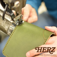 職人手作綠色皮革二折橫式小短夾，由手工縫製，展現精緻工藝。