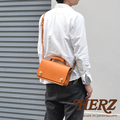 職人手作皮革經典兩用雙扣迷你單肩包，採用天然皮革，經典的駝色，配有可調節的肩帶和頂部提把，兩個金色旋轉鎖扣設計，適合日常搭配。
