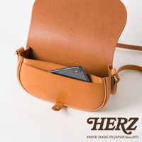 職人手作皮革迷你馬鞍包，採用棕褐色皮革製成，包身飽滿，翻蓋設計，內側可放入一支手機。