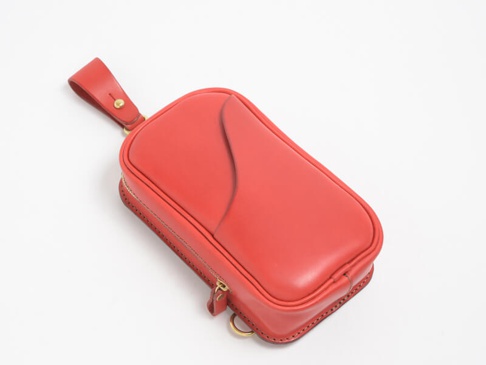 紅色職人手作皮革兩用斜背包，直立型設計，側面有拉鍊開合，頂部有皮革提把，搭配金色五金配件，整體呈現簡約質感。