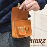 職人手作皮革高爾夫腰包，採用天然皮革材質，呈現溫潤的焦糖棕色。包身設計精巧，配有金屬扣環與三個專門放置高爾夫球的插槽，手工縫線清晰可見。