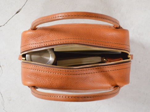 職人手作皮革Organ方形托特包 (G-47) M，採用淺棕色紋理皮革製成，方形簡約設計，頂部有拉鍊開合，露出內部筆記本和金屬隨身瓶。包身兩側有對稱的提把，縫線清晰。