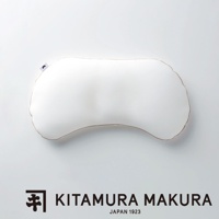 一個白色、彎曲形狀的豌豆枕，邊緣有細緻的縫線，枕頭上印有小小的黑色月亮標誌。