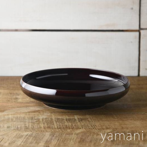 Tsudoi 赤飴釉美濃燒圓盤，呈現深棕色，表面光滑，具有光澤感，盤緣略微向上彎曲，置於木質桌面和白色木板背景上。