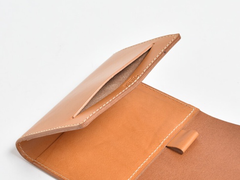 職人手作皮革A6記事本書套，淺棕色皮革，內側有插槽與固定帶，白色車縫線。