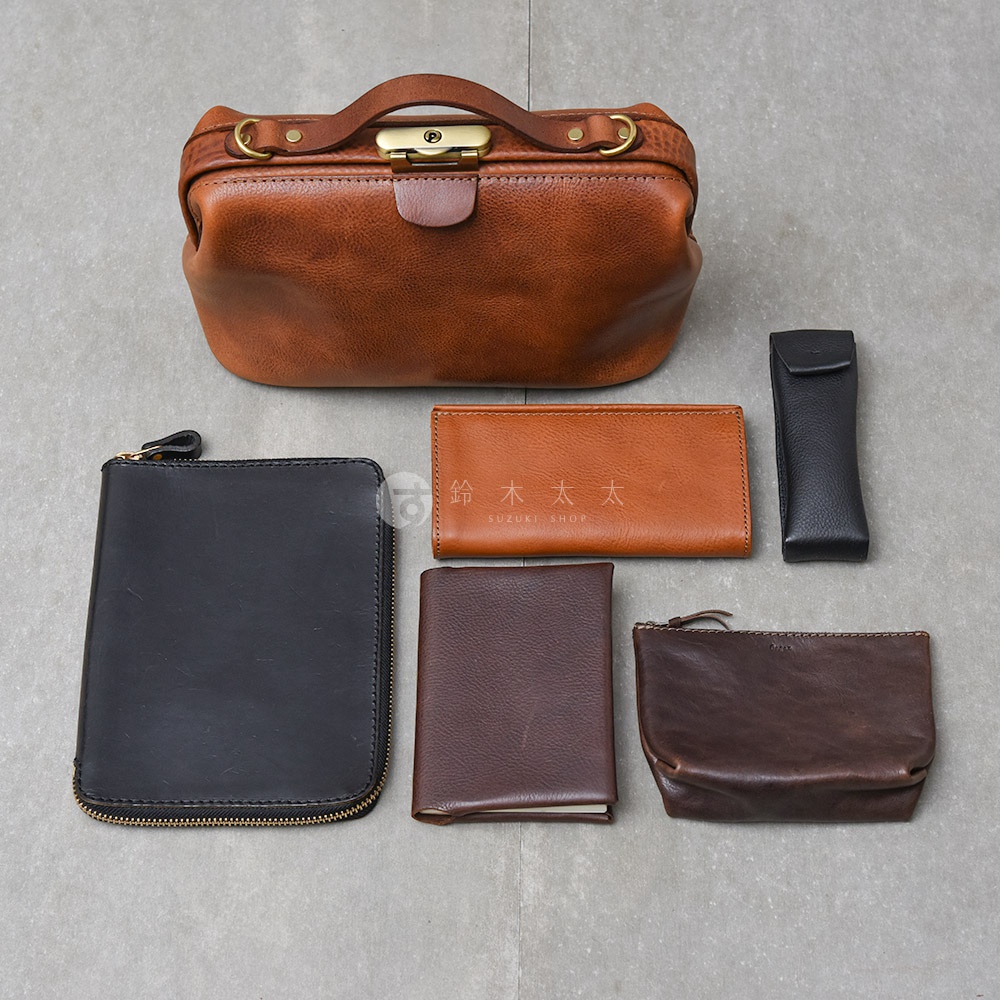 日本HERZ 職人手作皮革Organ鎖孔式大開口肩背包 M-7，搭配同色系或對比色皮革製成的小配件，包含黑色拉鍊長夾、棕色皮夾、棕色小收納包，以及一個黑色筆套。