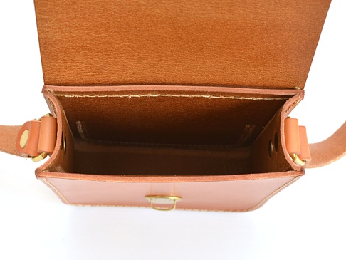 職人手作皮革經典皮扣單肩包 (CP-97) 側邊視角，焦糖色牛皮材質，包身結構完整，金屬扣環與皮帶調節扣清晰可見。