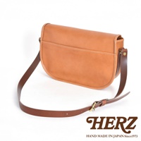 一款淺棕色皮革製成的斜背包，帶有深棕色皮革肩帶和搭扣。包包設計簡約，線條流暢，正面有一個翻蓋和一個外袋。