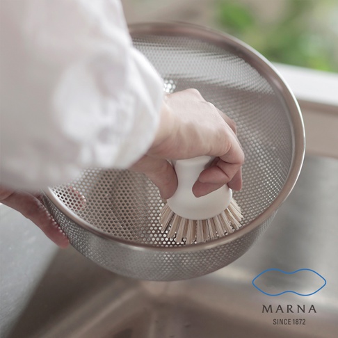 白色抗菌刷毛廚房清潔刷，刷毛呈淺棕色，正在清潔不鏽鋼濾網。