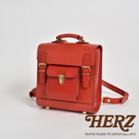 經典學院風迷你後背包，採用紅色皮革材質，配有金色金屬扣環和鎖扣，頂部有提把，側面有可調節的肩帶。