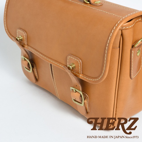 職人手作皮革單肩包，淺棕色天然皮革材質，配有黃銅釦環及裝飾，簡約設計，適合商務與休閒場合。