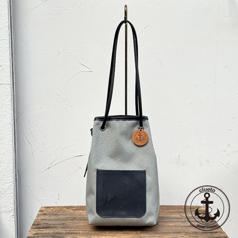 神戶clueto 灰色防潑水尼龍束口包，搭配黑色皮革提把和義大利皮革前袋，綴有船錨吊飾