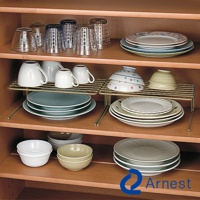 展示兩個黃銅色雙層碗盤收納掛架，架上擺放著多個白色馬克杯、彩色花紋碗盤、綠色碗盤及綠色淺碗。