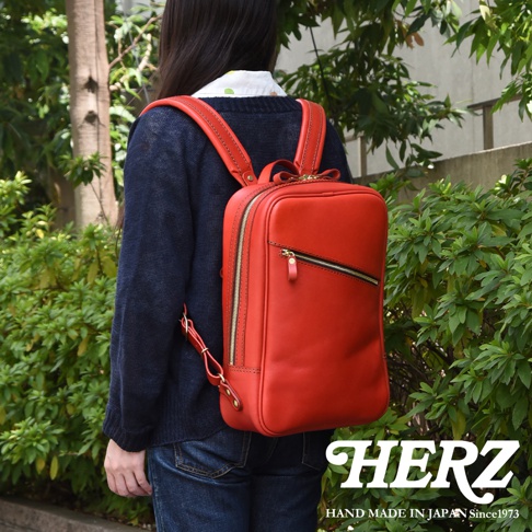 職人手作皮革長方型多口袋後背包，鮮紅色，設有拉鍊開合和多個口袋，搭配金色拉鍊和品牌標誌。