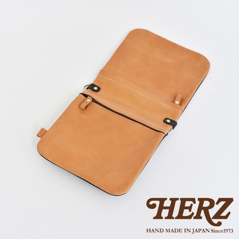 淺棕色皮革翻轉直式斜背包，拉鍊開合，附有兩個小拉鍊袋，皮革材質，金屬扣環，簡約設計。