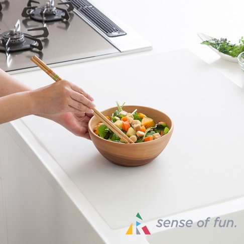 白色耐高溫料理台保護墊，上面擺放著一碗沙拉，一隻手正用木筷子夾取沙拉。