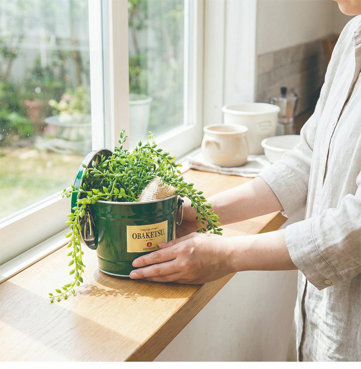 OBAKETSU 品牌的手工製多功能迷你桶，綠色桶身上有日文標示，內裝翠綠垂墜植物，放置在陽光灑落的窗台上。