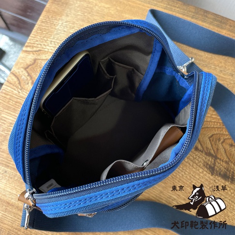 藍色石洗帆布散步包內部，有手機隔層和多個內袋。