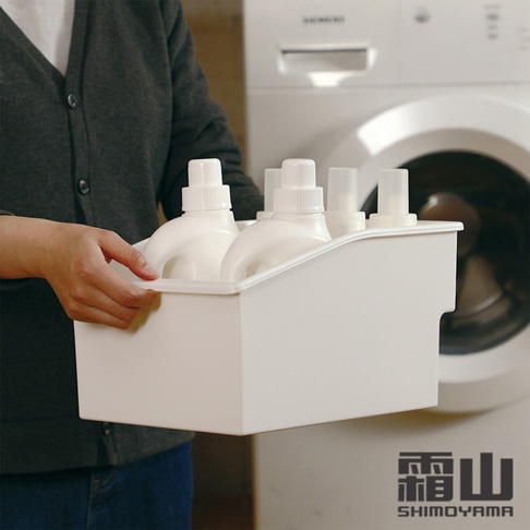 白色塑膠提把式收納籃，內含數瓶白色洗衣精或柔軟精，由一人手持，背景為洗衣機。