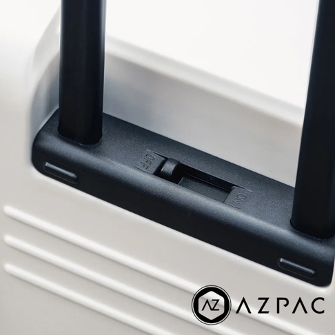 AZPAC Trucker 2.0 行李箱的黑色煞車開關特寫，開關上標示著「OFF」與「ON」，旁邊是行李箱的白色外殼及兩個黑色拉桿。
