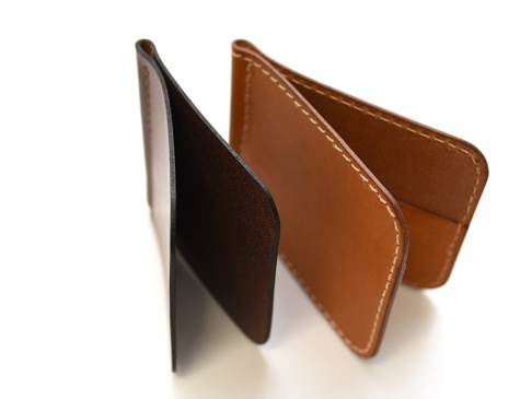 兩件式職人手作皮革橫式對折鈔票短夾，一件為深棕色，另一件為淺棕色，皆為真皮材質，以白色車線縫製，簡約而實用。