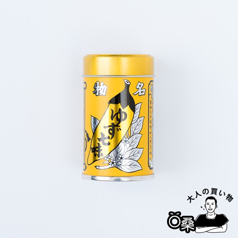 黃色金屬罐裝柚子七味粉，罐身印有黑色的辣椒圖案、綠葉與白色小花，以及日文「柚子七味」字樣。