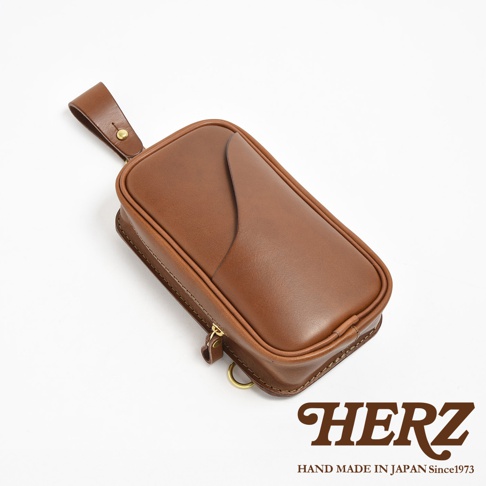 HERZ 職人手作咖啡色皮革兩用直立型斜背包，帶有可拆式肩背帶，近景拍攝。
