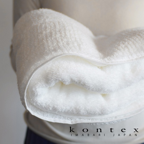 一條白色極柔蓬鬆的今治毛巾，質地細緻，邊緣有縫線。