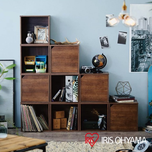 深棕色木紋組合收納櫃，共九個立方體格子，其中有幾個格子配有門片，展示書籍、地球儀、相機、裝飾品及收納盒等物品。