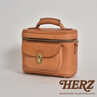 職人手作皮革相機包，經典棕色，柔軟皮革材質，圓潤造型，頂部設有提把及拉鍊，前方有一個翻蓋式口袋，並以金屬釦固定。