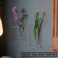 兩個黃銅金屬線製成的方形掛壁花器，其中一個花器插有紫色花束，另一個花器插有綠色花苞，均置於玻璃試管中。