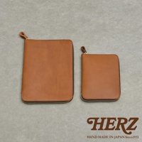 兩個棕色皮革記事本收納包，一個較大一個較小，皆有拉鍊開合，底部印有HERZ HAND MADE IN JAPAN Since1973字樣