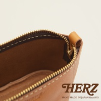 職人手作皮革三角收納包，展示棕褐色皮革材質，帶有金色拉鍊和縫線細節，內部空間可見。