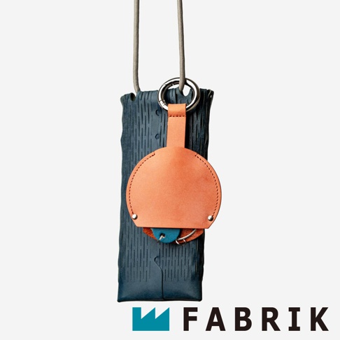 FABRIK 品牌標誌旁的皮革圓形收納鑰匙圈，懸掛在深藍色波浪紋的長形收納袋上，搭配金屬掛環和粗繩。