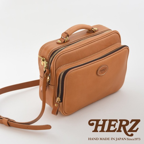 職人手作皮革兩用商務公事包，經典棕色，光滑皮革材質，設有頂部提把、多個拉鍊隔層和可拆卸肩帶，適合商務場合。