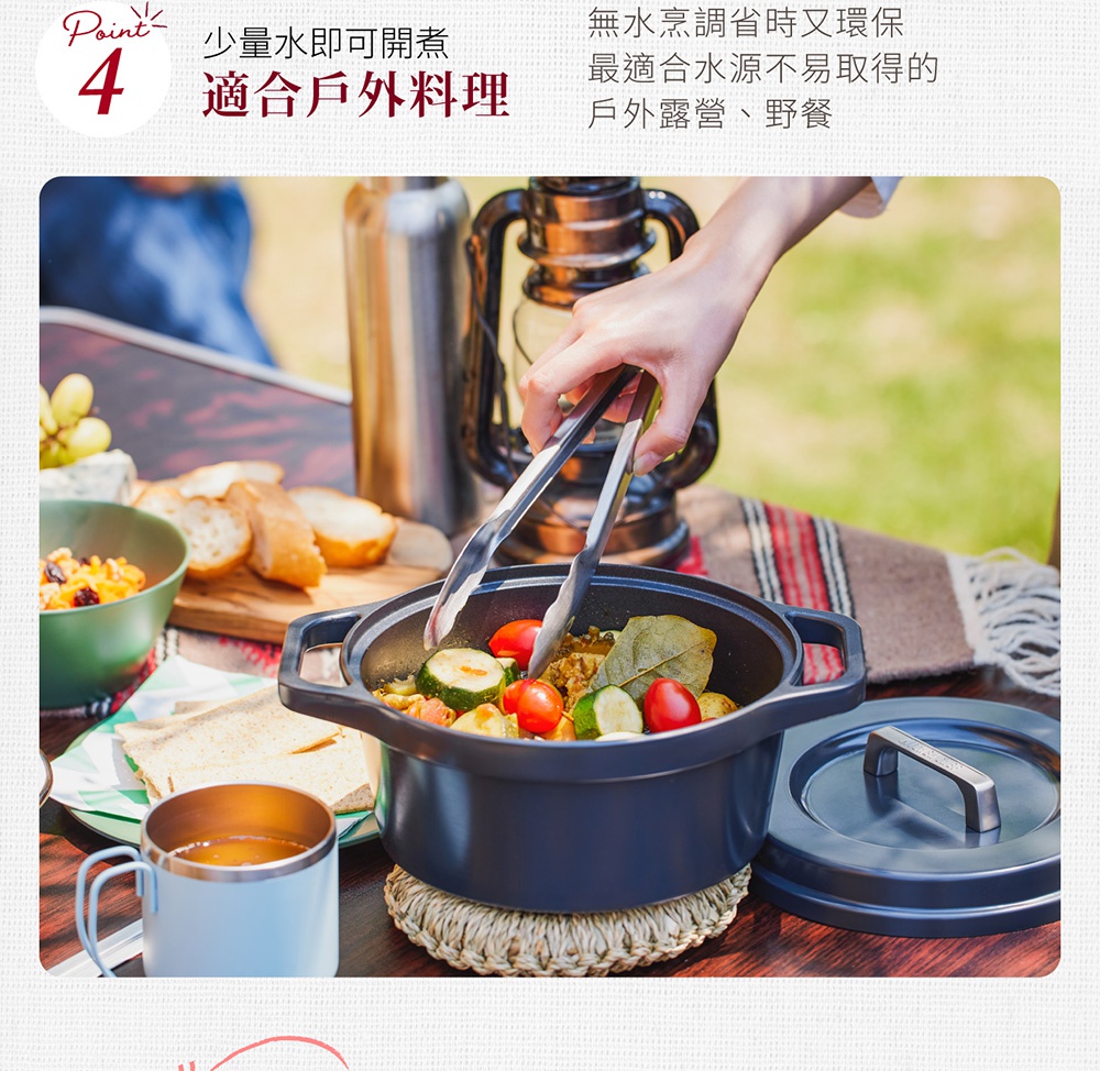 一個深灰色萬用無水調理鍋，鍋內有雞肉、番茄、櫛瓜和香料，正由夾子夾取食材。鍋旁另有一鍋蓋。