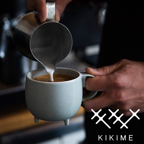 淺藍色美濃燒斑石釉球型馬克杯，有三個小腳，正被倒入牛奶，營造出豐富的咖啡拉花。